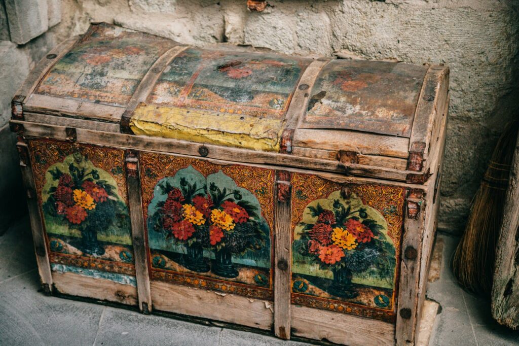 Ornate antique wooden chest with floral paintings in a historic setting.