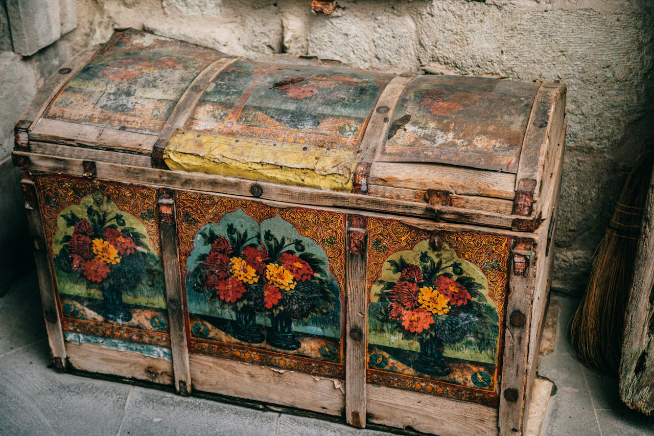 Ornate antique wooden chest with floral paintings in a historic setting.